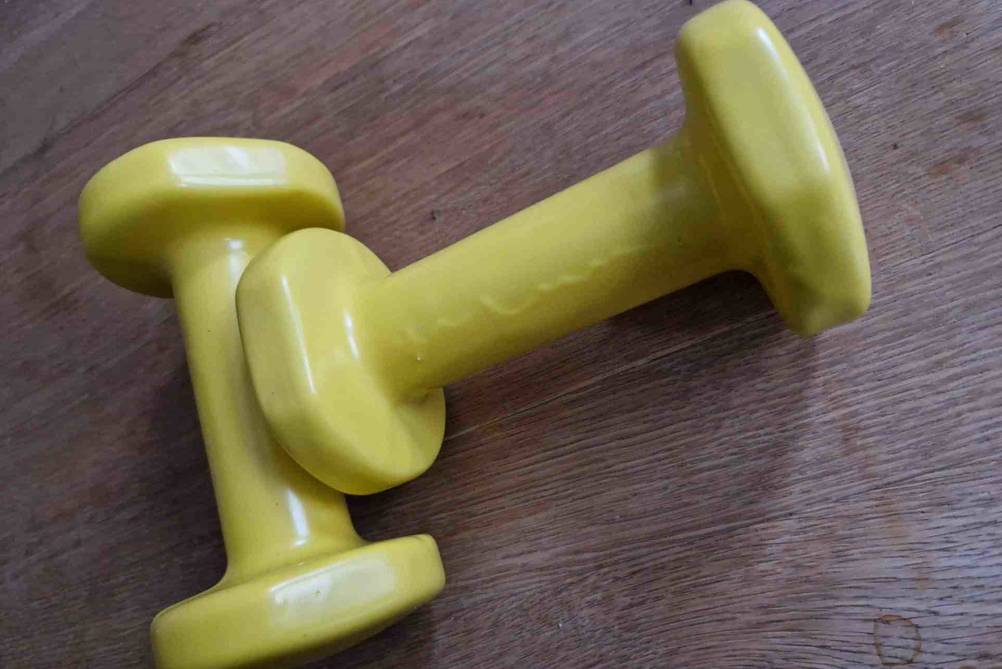 Im Test: Zwei Decathlon Kurzhanteln in gelb liegen auf einem Tisch.
