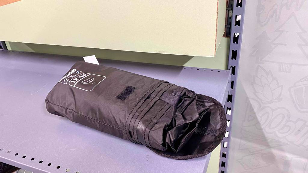 Regenponcho Fahrrad getestet: Verpackter Poncho liegt in Metallregal.