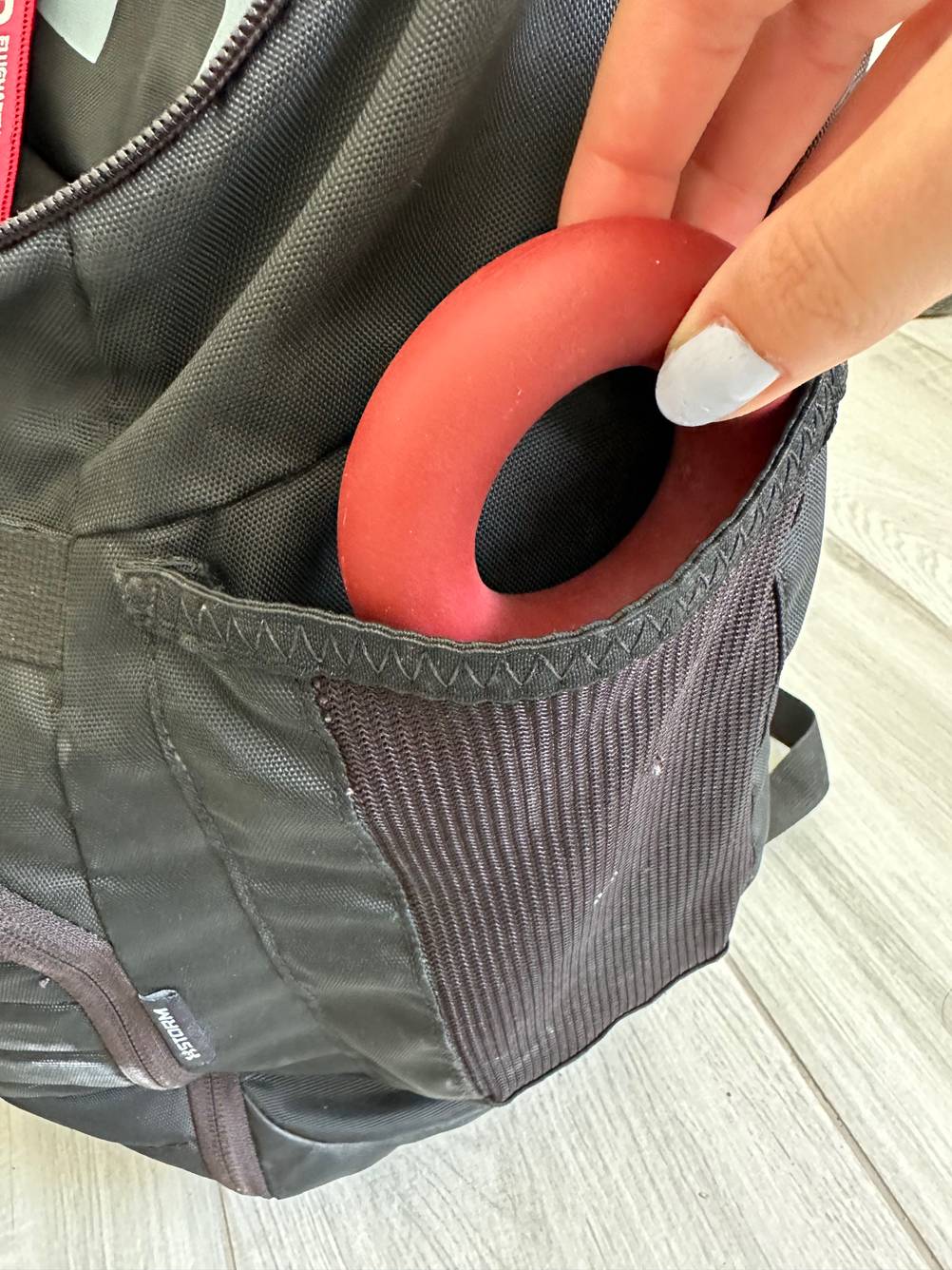 Ein Hand steckt einen Handtrainer-Ring in eine kleine schwarze Tasche.