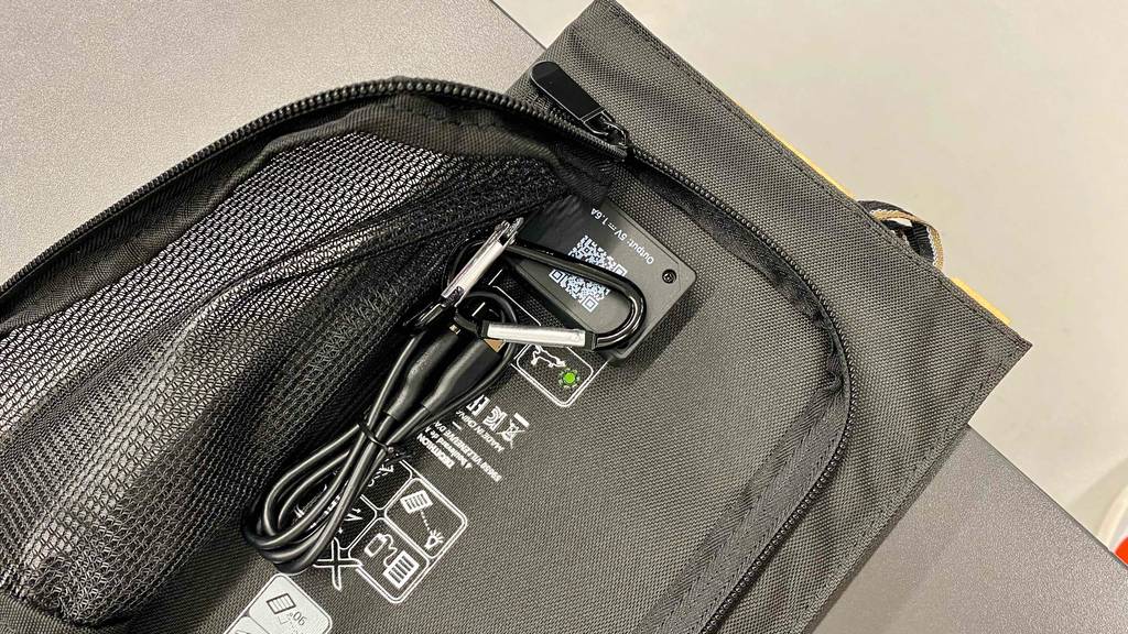 Geöffnete schwarze Tasche inklusive Karabiner und USB-Kabel von einem getesteten Solarpanel.