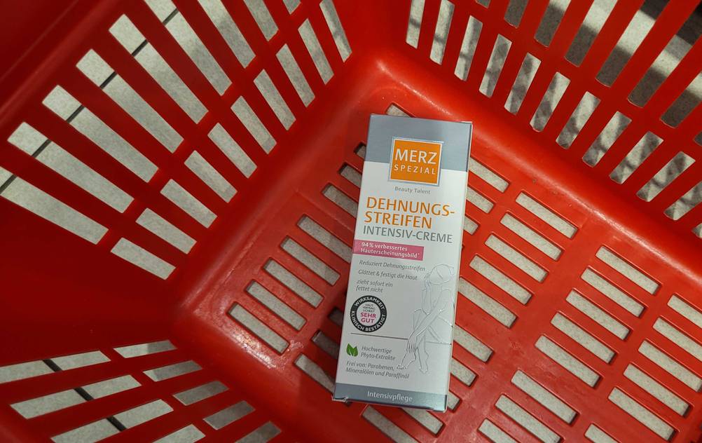Eine getestete Dehnungsstreifen-Creme liegt in einem roten Einkaufskorb.