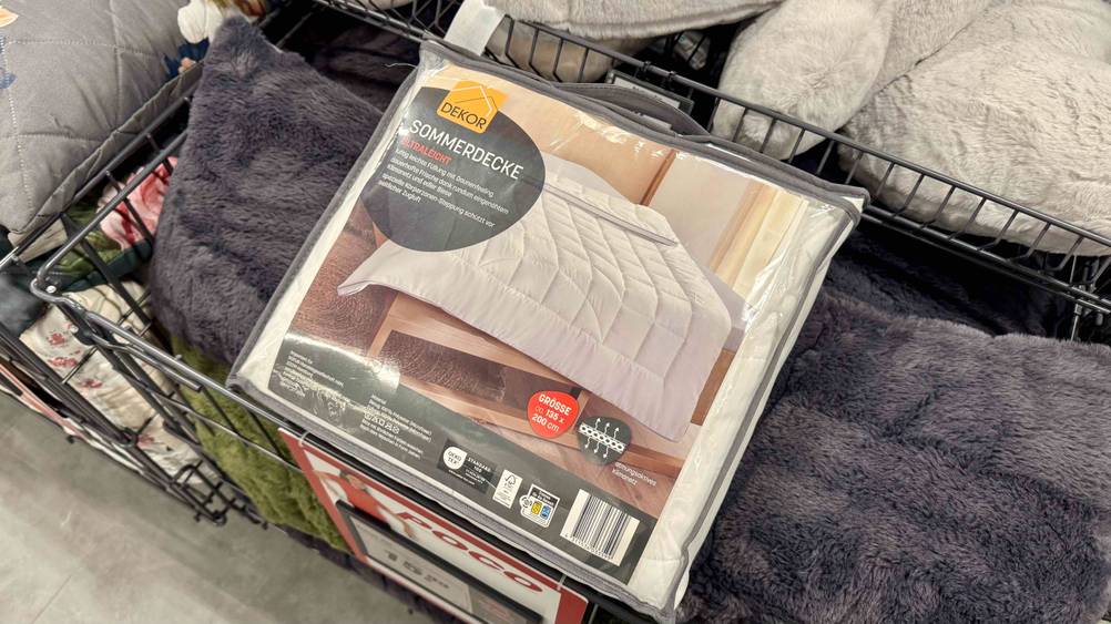 Eine verpackte Sommerdecke liegt zum testen auf Flauschkissen.
