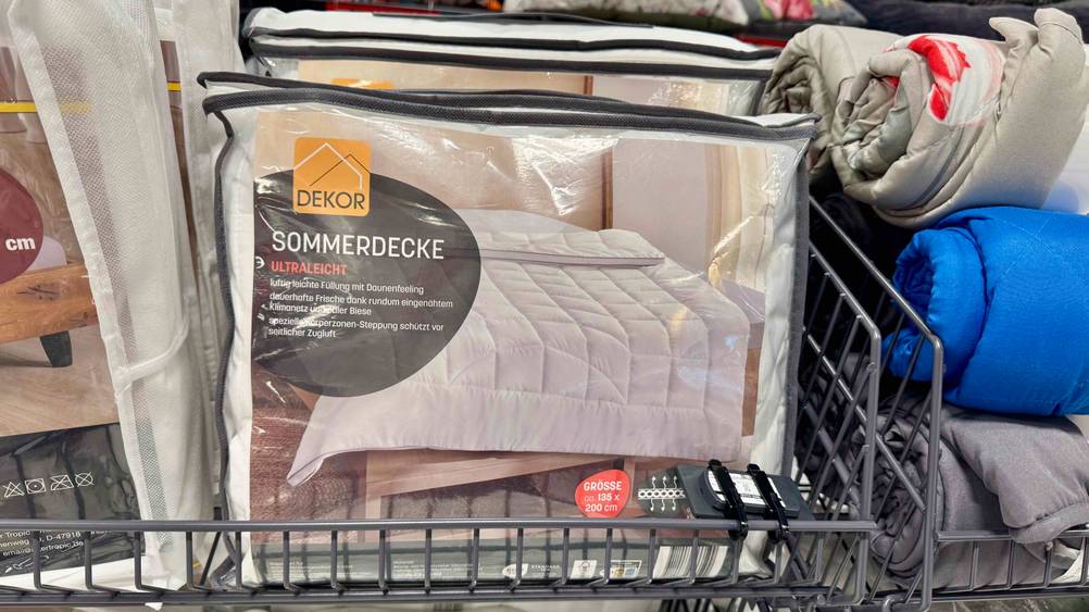 Im Test: Mehrere verpackte Sommerdecken stehen hintereinander in einem Regal.
