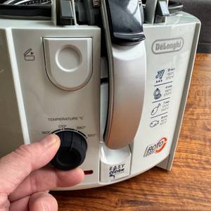 Eine Hand dreht am Temperaturregler der DeLonghi F 28311