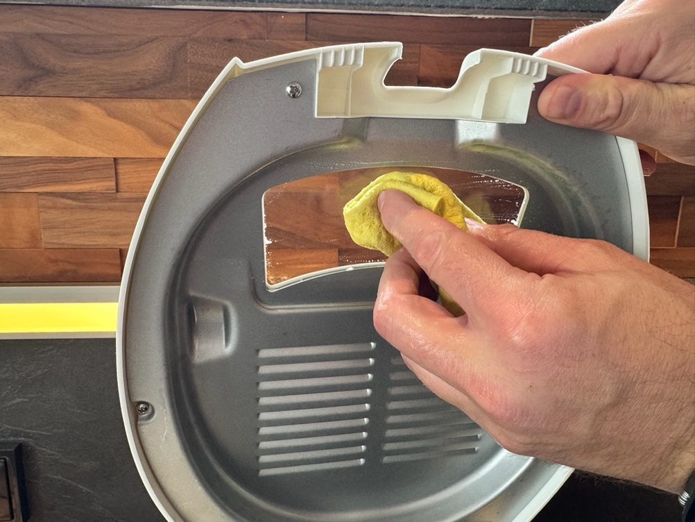 Eine Hand reinigt das Fenster der DeLonghi F 28311