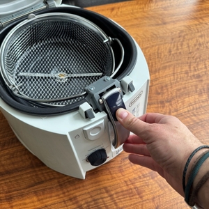 Eine Hand verriegelt den Korb der DeLonghi F 28311