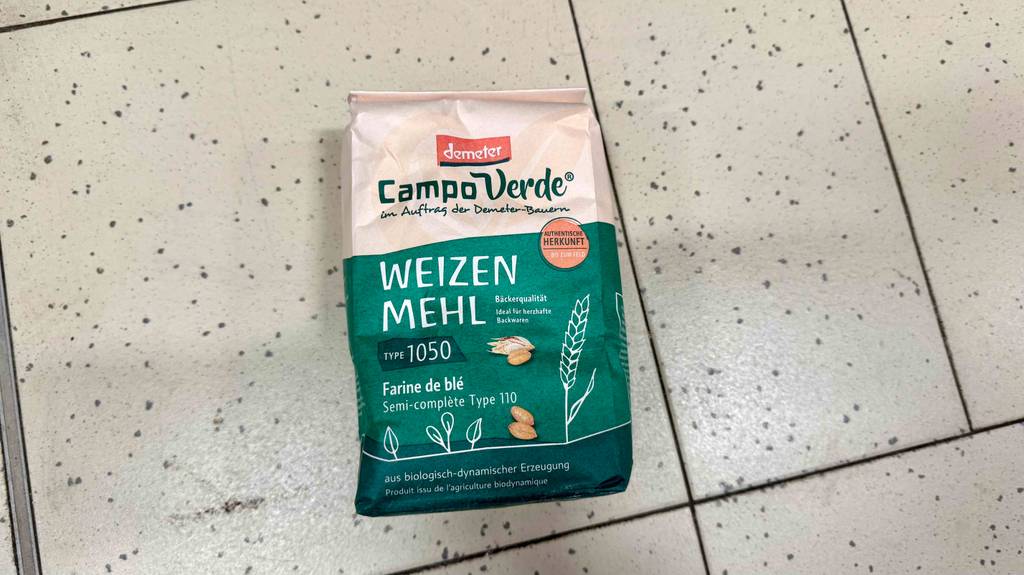 Weizenmehl 1050 im Test: Eine grüne Demeter-Packung liegt auf einem Fliesenbelag.