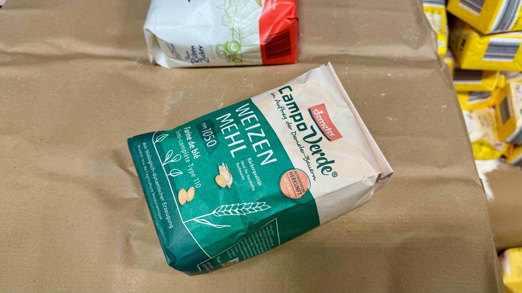 Getestet: Weizenmehl 1050 in einer grünen Demeter-Packung liegt auf einem braunen Packpapier neben einer Packung Zucker.