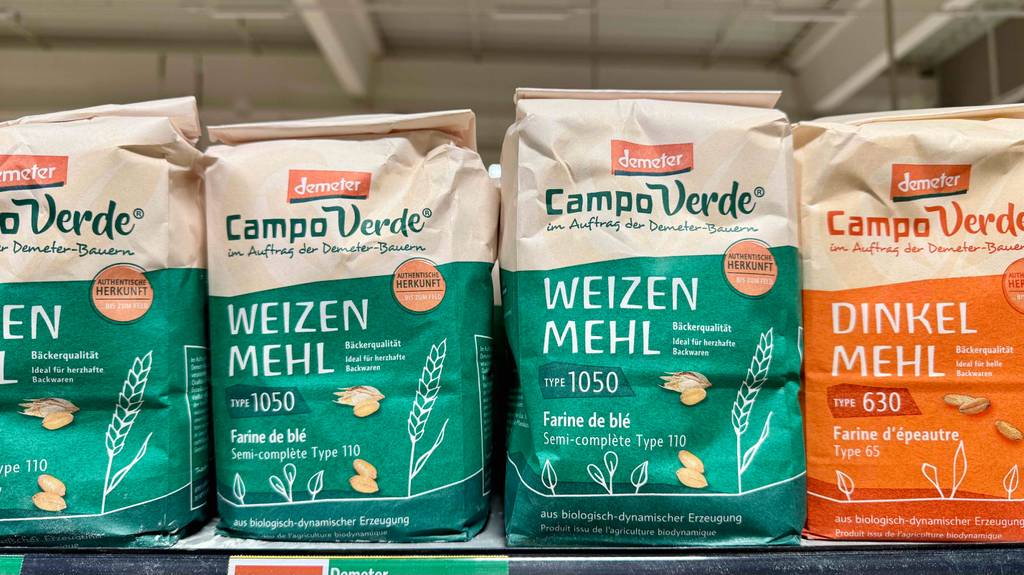 Mehrere grüne Packungen mit Weizenmehl 1050 im Test stehen neben Dinkelmehl auf einem Verkaufsregal.