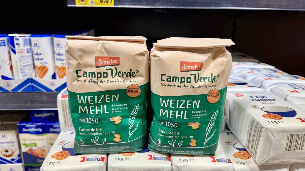 Getestetes Weizenmehl 1050 in grünen Demeter-Packungen befindet sich auf einem Regal mit Zuckerpackungen.