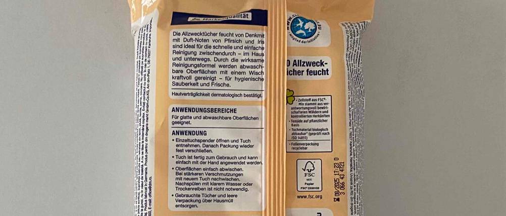 Nahaufnahme der Produktinformationen von getesteten Feuchttüchern, die in einer Kunststoffverpackung auf einer weißen Oberfläche liegen.