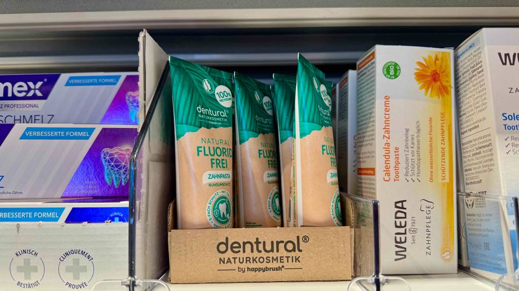 Getestet: Zahnpasta ohne Fluorid steht in der Tube auf einem Regal mit verschiedenen Zahnpastasorten.
