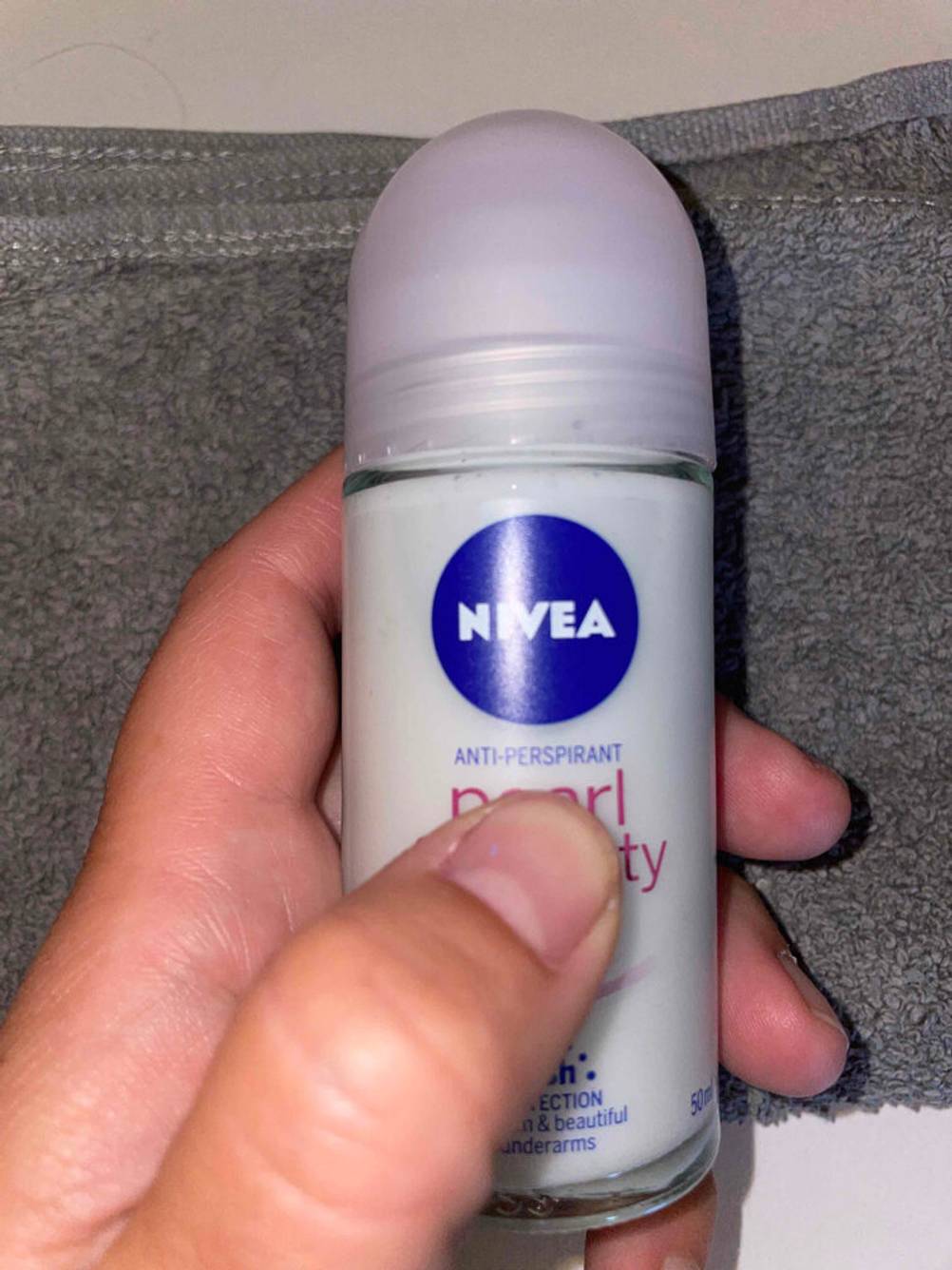 Deo-Roller für Damen getestet: Eine Hand hält ein Deo vor ein graues Handtuch.
