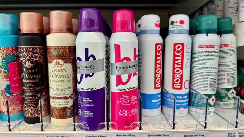 Mehrere Dosen des getesteten Deospray Damen neben anderen Produkten in einem Verkaufsregal.
