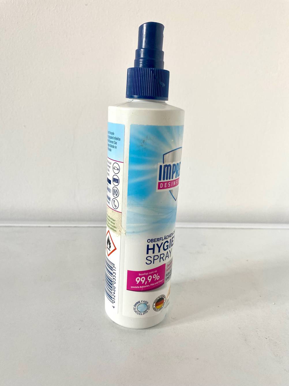 Seitenansicht einer Flasche Desinfektionsspray auf einer hellen Fläche.