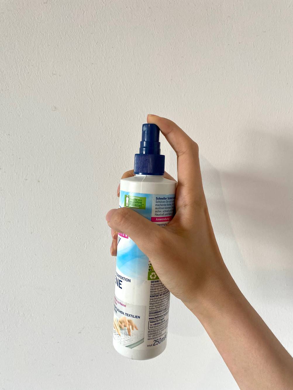Eine Hand hält ein Desinfektionssprays 