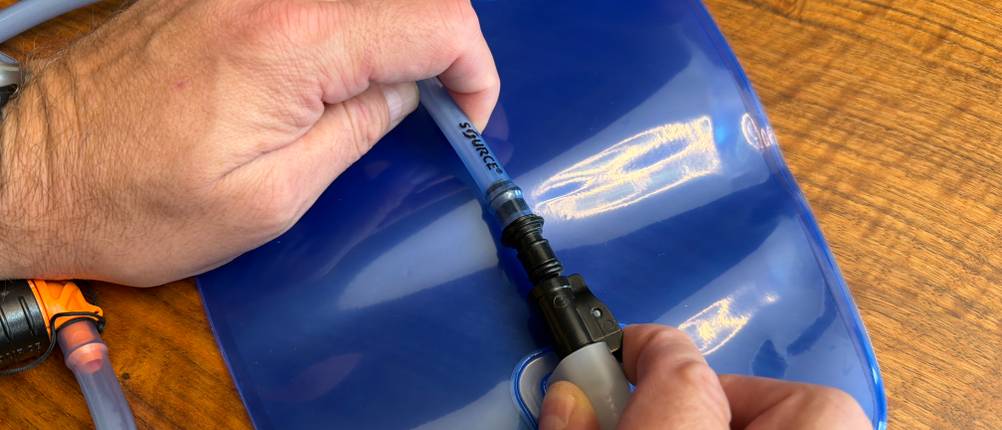 Eine Hand befestigt den Schlauch der Deuter Streamer 3.0 l