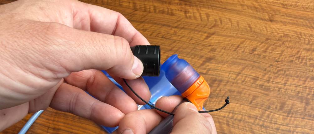 Eine Hand befestigt die Kappe auf dem Mundstück der Deuter Streamer 3.0 l