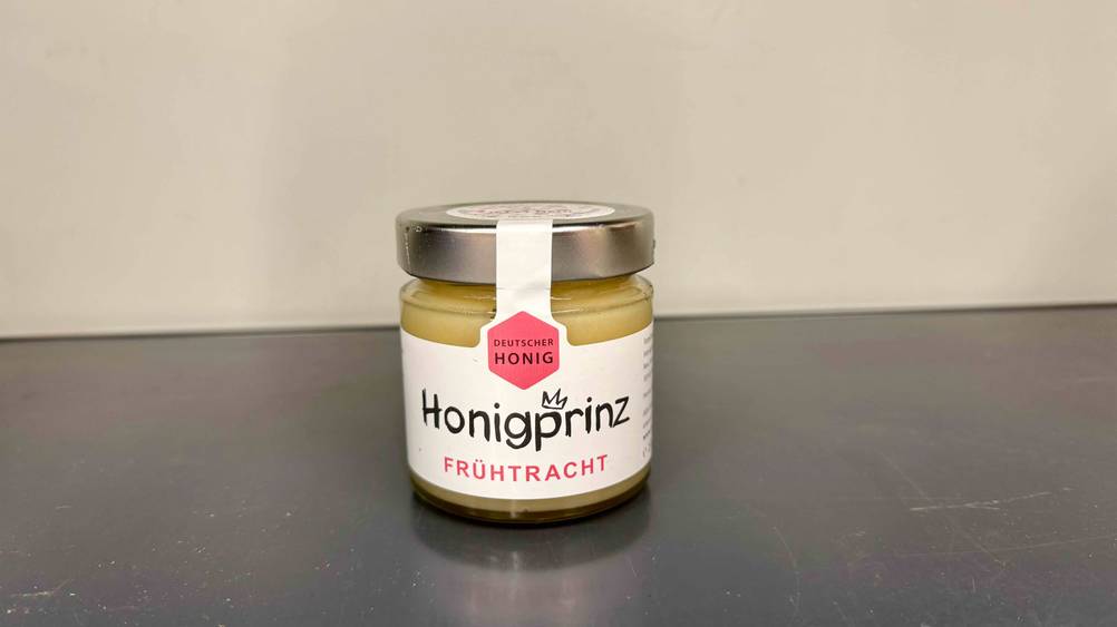 Deutscher Honig im Test: Ein Glas von vorne vor einer hellen Wand.
