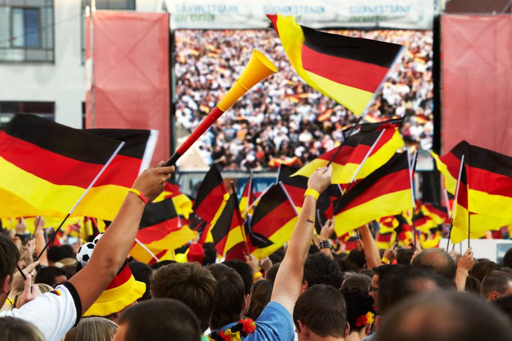Public Viewing in Deutschland: Viele Menschen mit Deutschland-Trikots und Fahnen vor einer Leinwand.