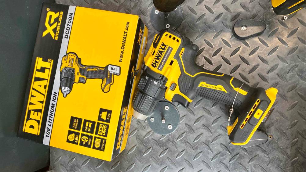 Ein DeWalt-Akkuschrauber im Test auf einer Metallfläche liegend, daneben die Originalverpackung.