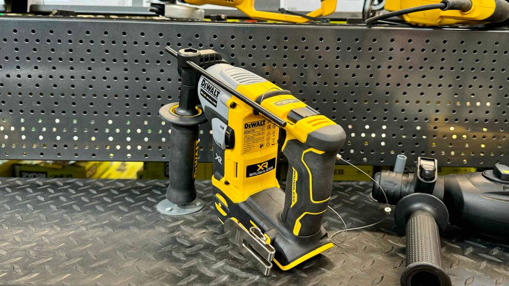 Dewalt-Bohrhammer im Test: Ein Gerät von hinten auf einem Regal neben anderen Geräten.