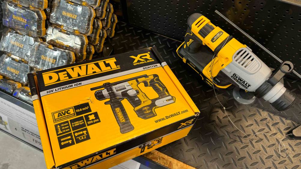 Ein getesteter Dewalt-Bohrhammer von oben neben seiner Originalverpackung auf einem Metallregal.