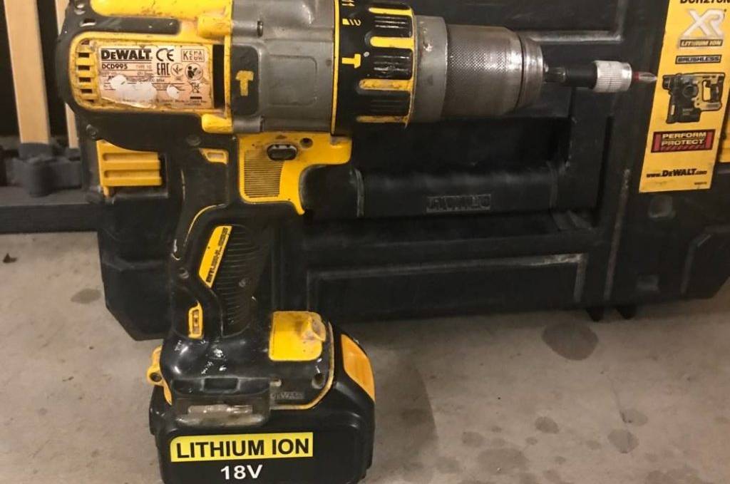 Getesteter Akku-Bohrschrauber im schwarz-gelben Design DCD777S2T von DeWalt befindet sich vor dem Transportkoffer auf einem grauen Boden.