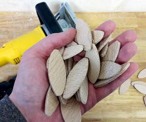 Hand mit Dübeln und Lamellofräse DeWalt DW682K