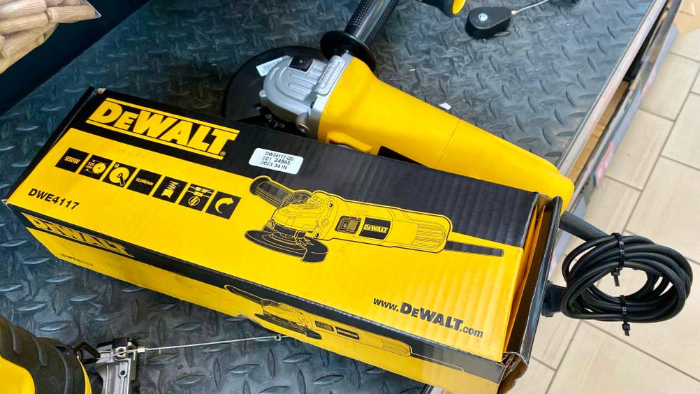 Ein getesteter DeWalt-Winkelschleifer liegt hinter seiner Originalverpackung auf einer dunklen Fläche.