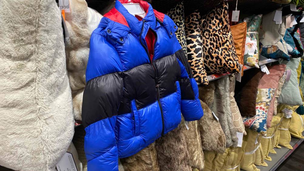 Getestet: Eine Kinder-Winterjacke für Jungen hängt in einem Regal neben Kissen.