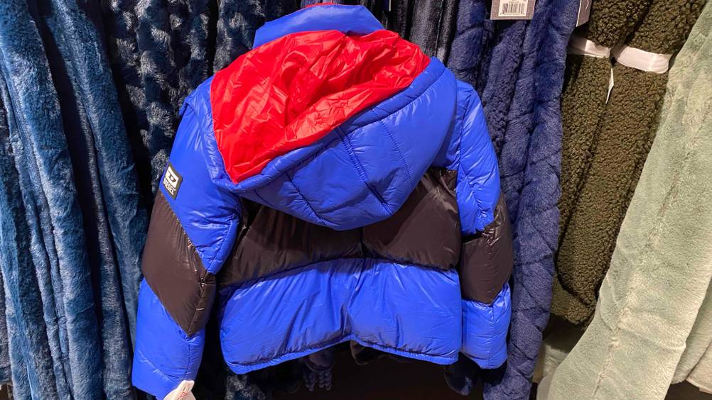 Eine getestete Kinder-Winterjacke für Jungen von hinten vor mehreren Decken.
