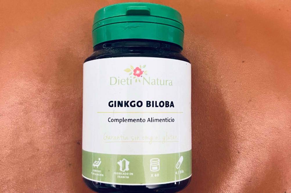 Ginkgo-Tabletten getestet: Eine Plastikdose mit grünem Schraubverschluss von Dieti Natura liegt auf einem rostroten Untergrund.