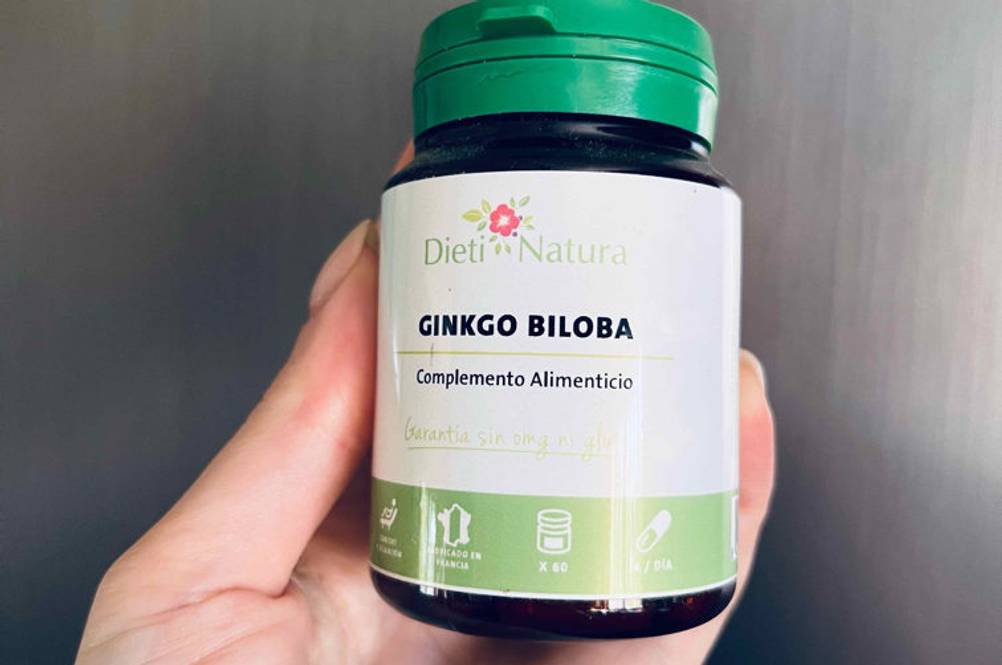 Ginkgo-Tabletten im Test: eine Hand hält Plastikdose mit grünem Schraubverschluss von Dieti Natura vor grauer Wand.