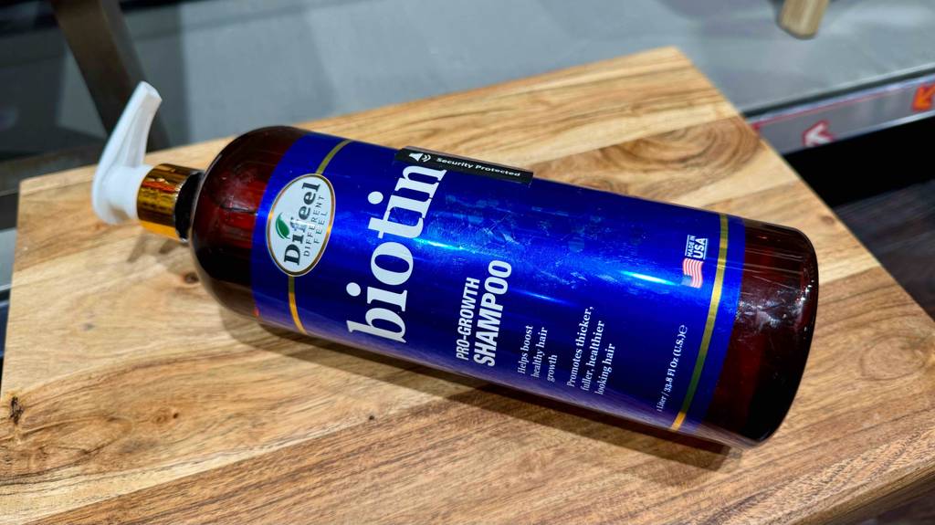 Ein Spender mit getestetem Biotin-Shampoo liegt auf einem Holzhocker.