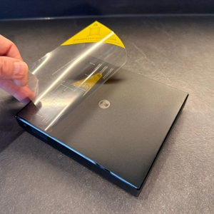 Eine Hand zieht eine Folie von der digitalen Timemore-Kaffeewaage