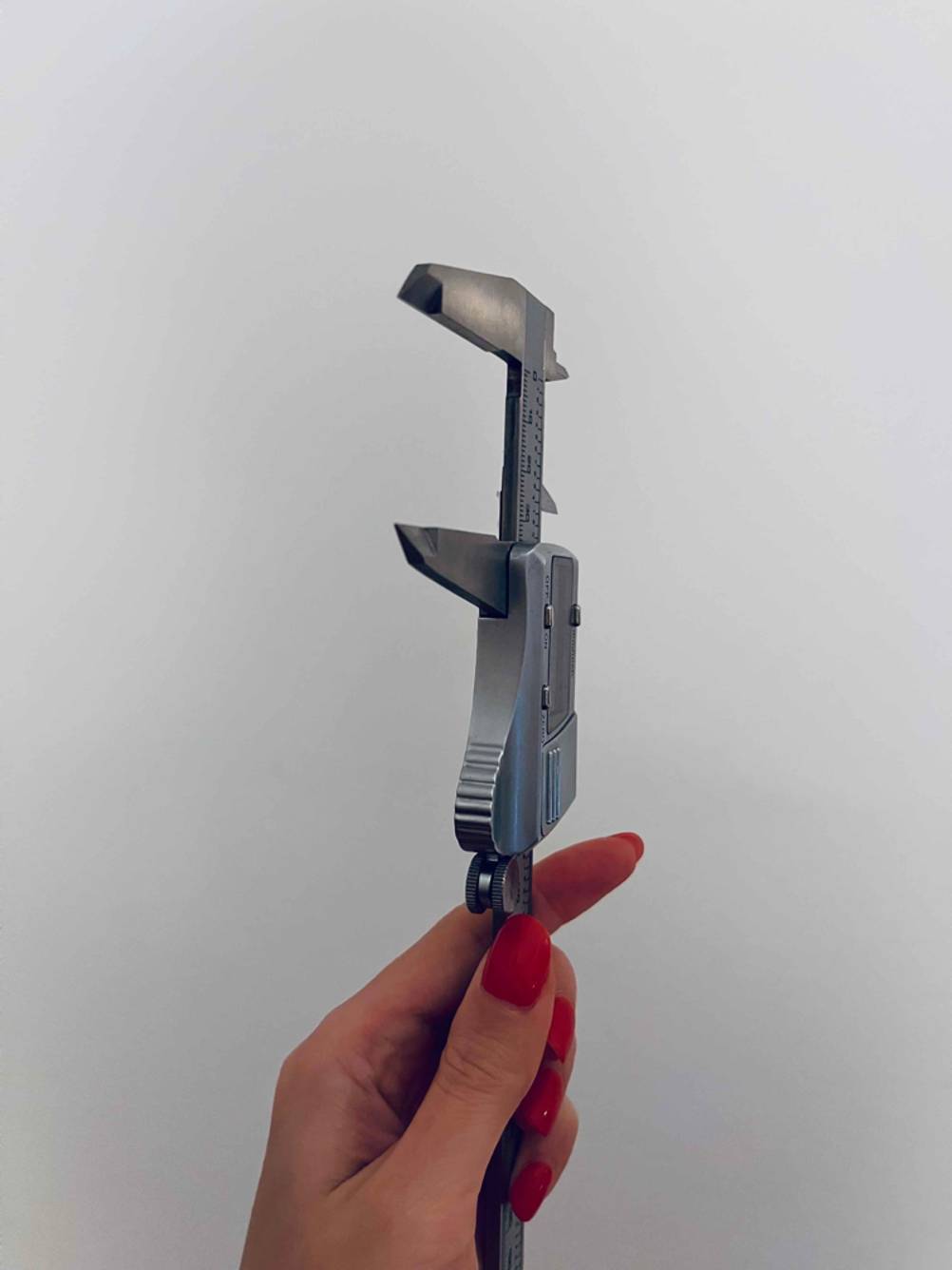 Im Test: Eine Hand hält einen digitalen Messschieber vor eine helle Wand.