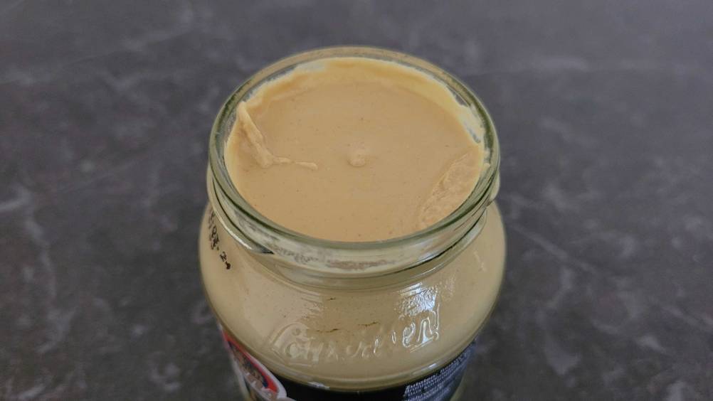 Auf dem Küchentisch befindet sich ein Glas mit getestetem Dijon-Senf.