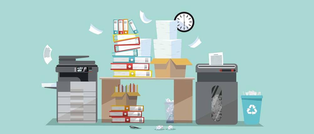 Ein Schreibtisch im Chaos: Papierstapel, Drucker und Reißwolf