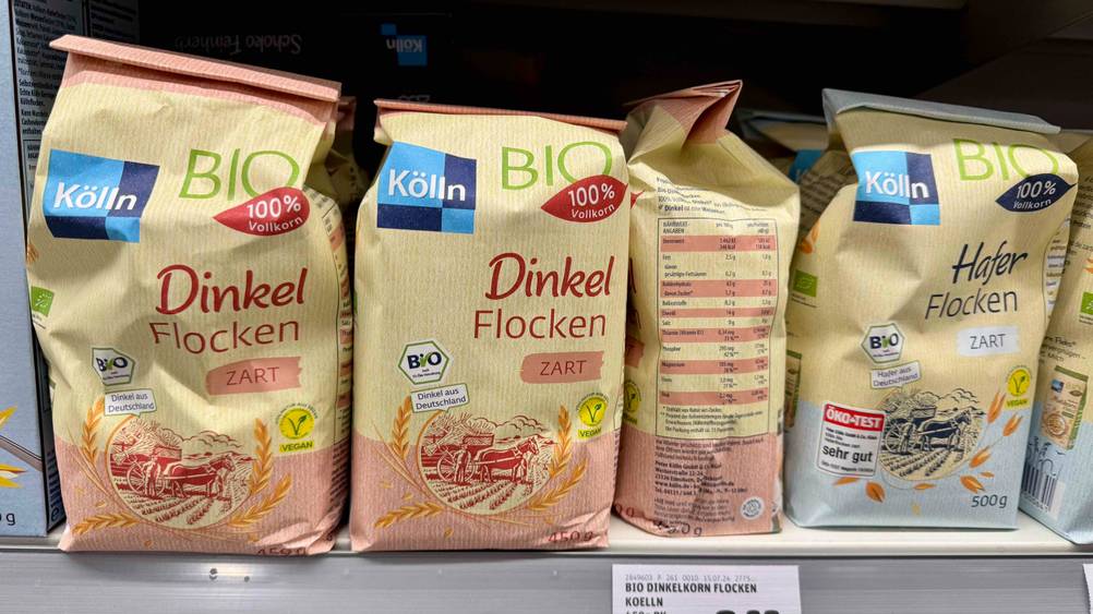 Mehrere Packungen der Dinkelflocken im Test in einem Verkaufsregal neben anderen Produkten.