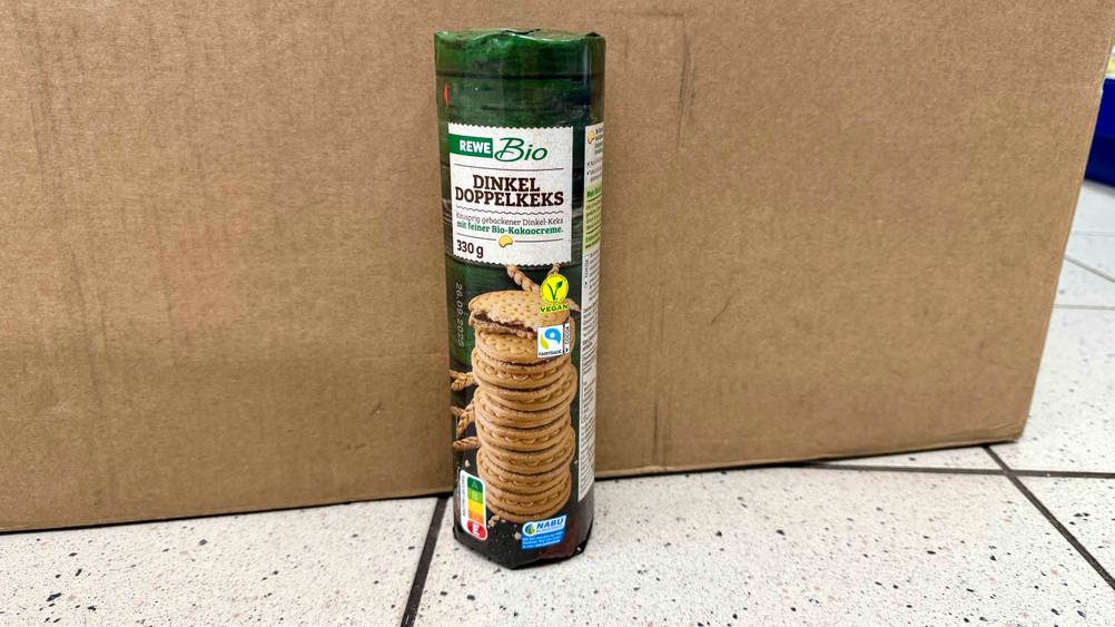 Vor einem Karton steht eine Packung Dinkelkekse im Test auf dem Boden.