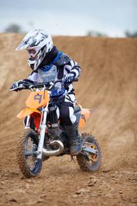 Ein Kind mit Schutzausrüstung und Helm auf einem Dirtbike.