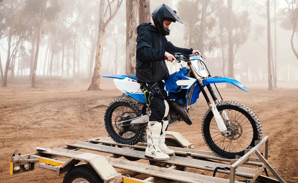 Ein Mann verlädt sein Dirtbike auf einen Anhänger.
