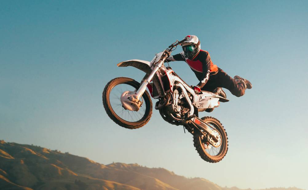 Ein Fahrer führt einen Sprung-Trick auf einem Dirtbike vor.