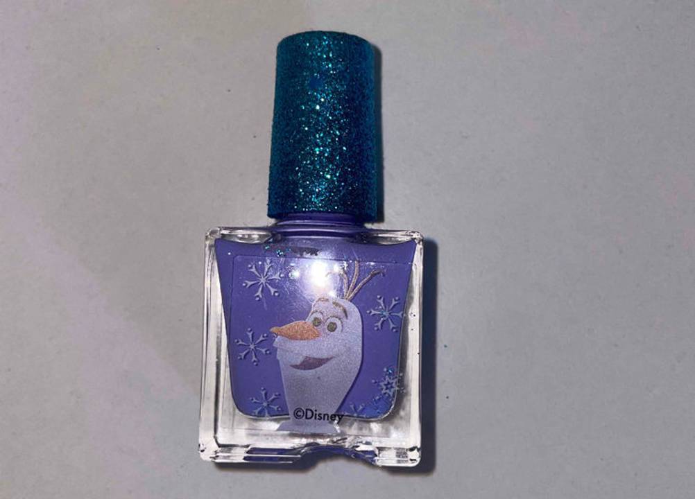 Ein Nagellack für Kinder im Olaf-Design liegt auf einer weißen Fläche zum testen.