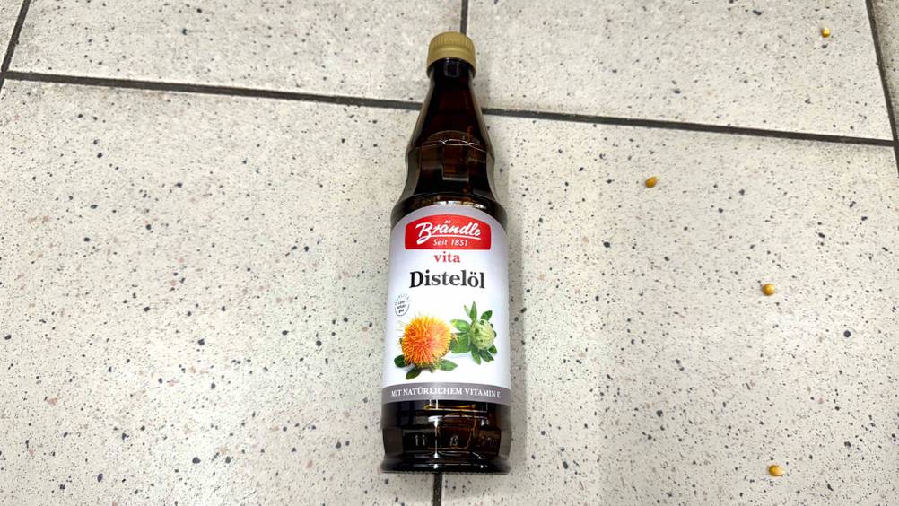 Distelöl im Test: Eine Flasche liegt auf einem Fließenboden.