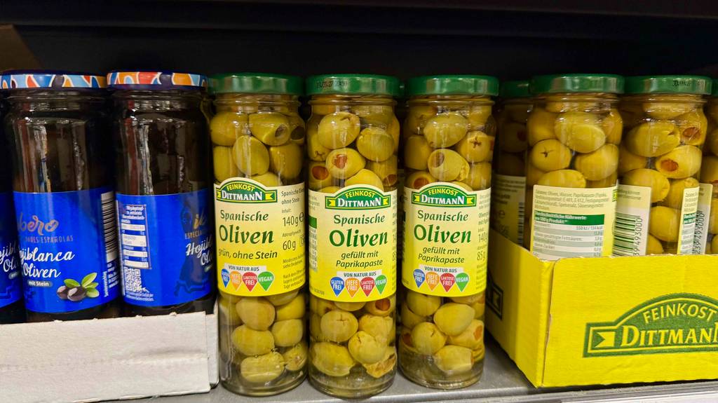 Spanische Oliven im Test: Mehrere Gläser stehen zwischen anderen Olivensorten in einem Regal.
