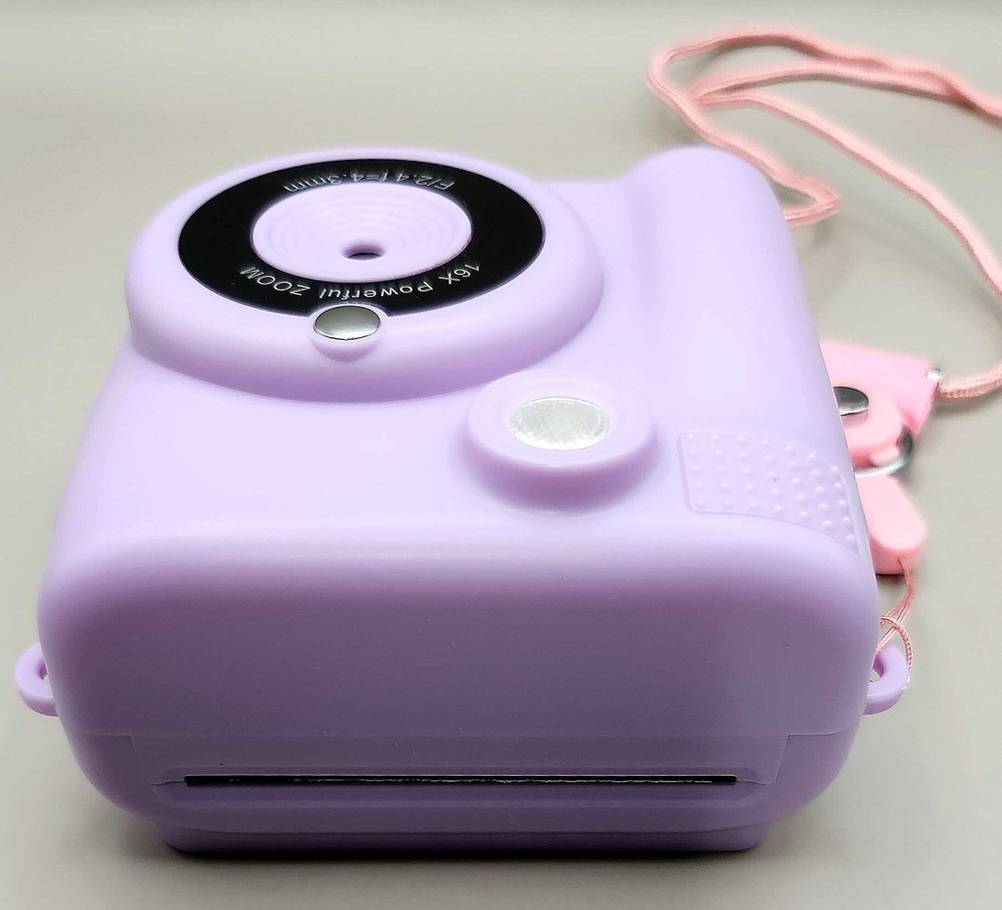 Kinderkamera-Test: Ein lilafarbenes Modell liegt mit Blick auf das Objektiv und den Blitz auf einer weißen Oberfläche.