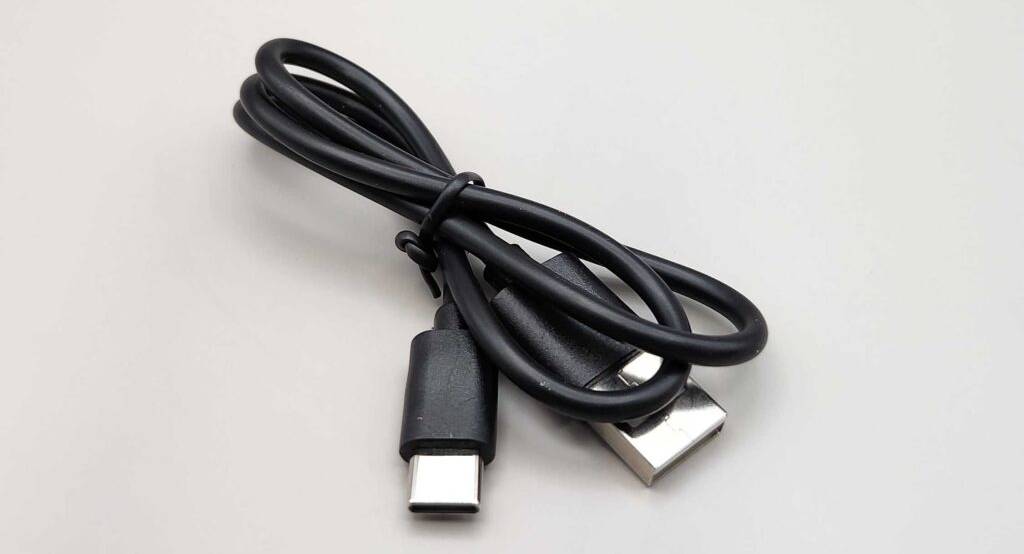 Kinderkameras im Test: Ein schwarzes USB-Kabel liegt auf einer weißen Oberfläche.