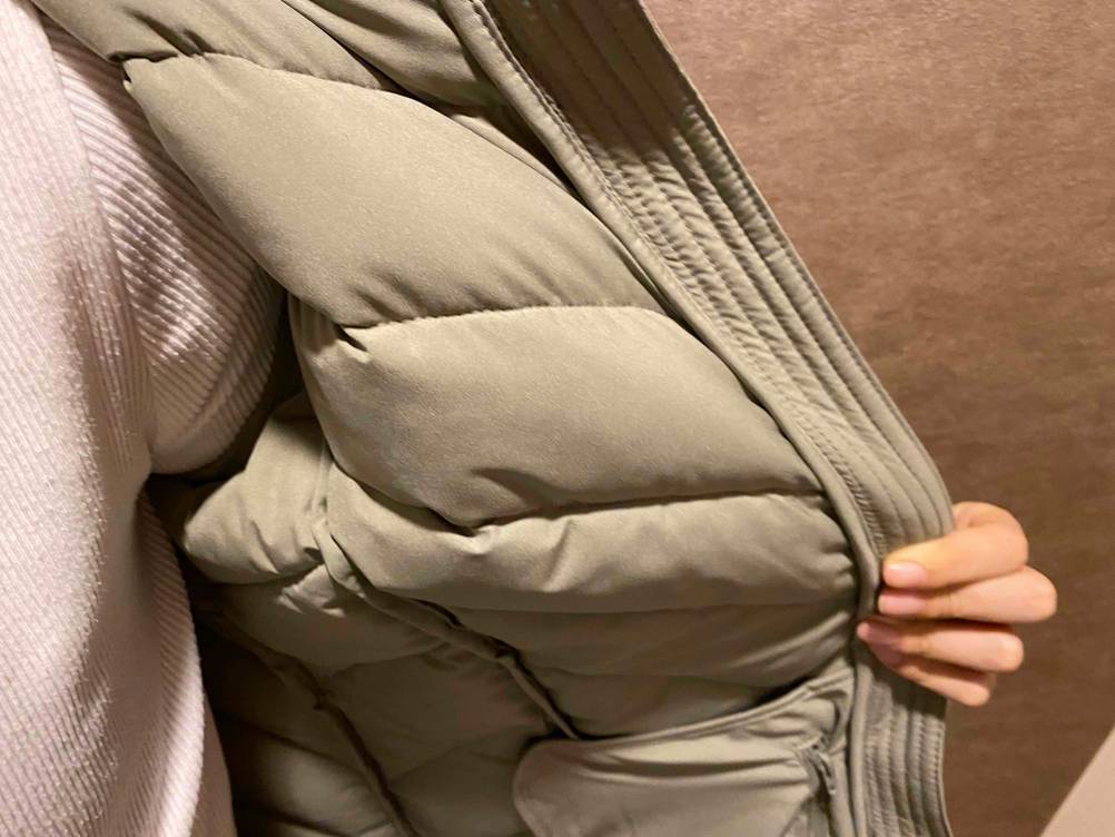 Damen-Daunenjacke im Test: Hand macht eine angezogene Damen-Daunenjacke für Damen auf und zeigt die Innenseite.